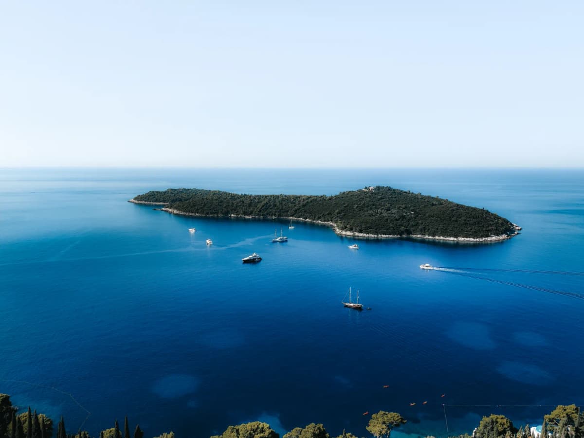 Stunning aerial view of an island in Dubrovnik, Croatia surrounded by turquoise waters and boats.