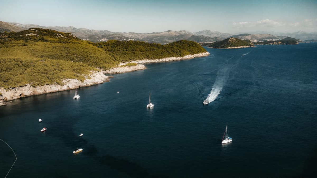 Scenic aerial shot of boats sailing near Lopud Island's lush coastline in Croatia.