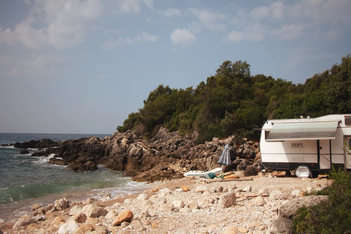A serene camping scene with an RV on the rocky coast of Vlorë County, Albania.